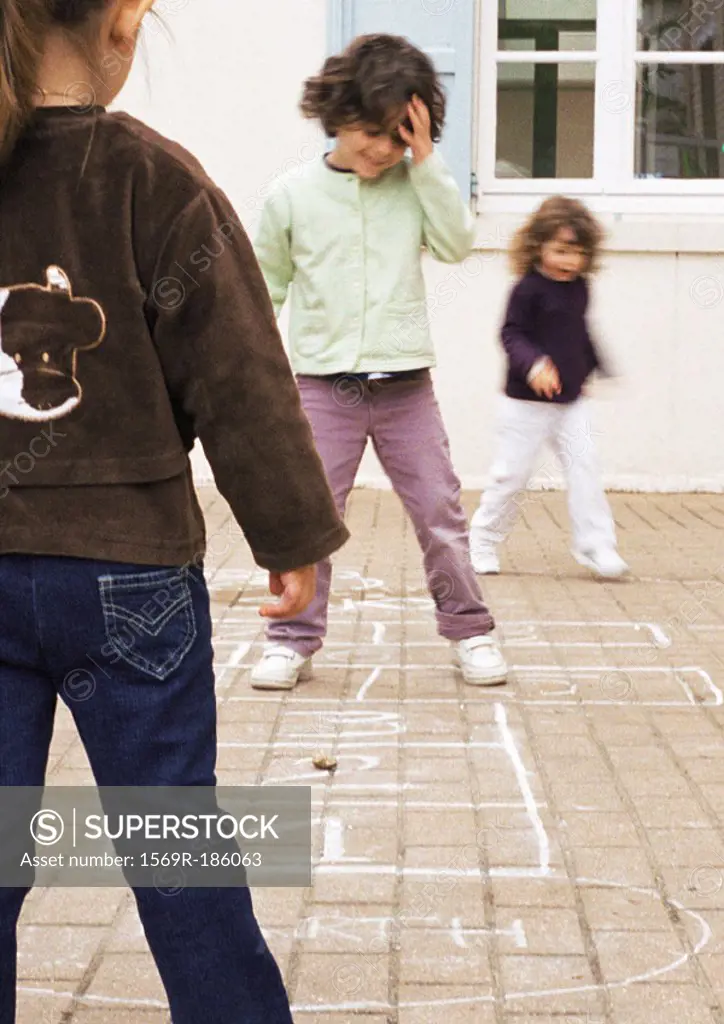 Three children playing hopscotch