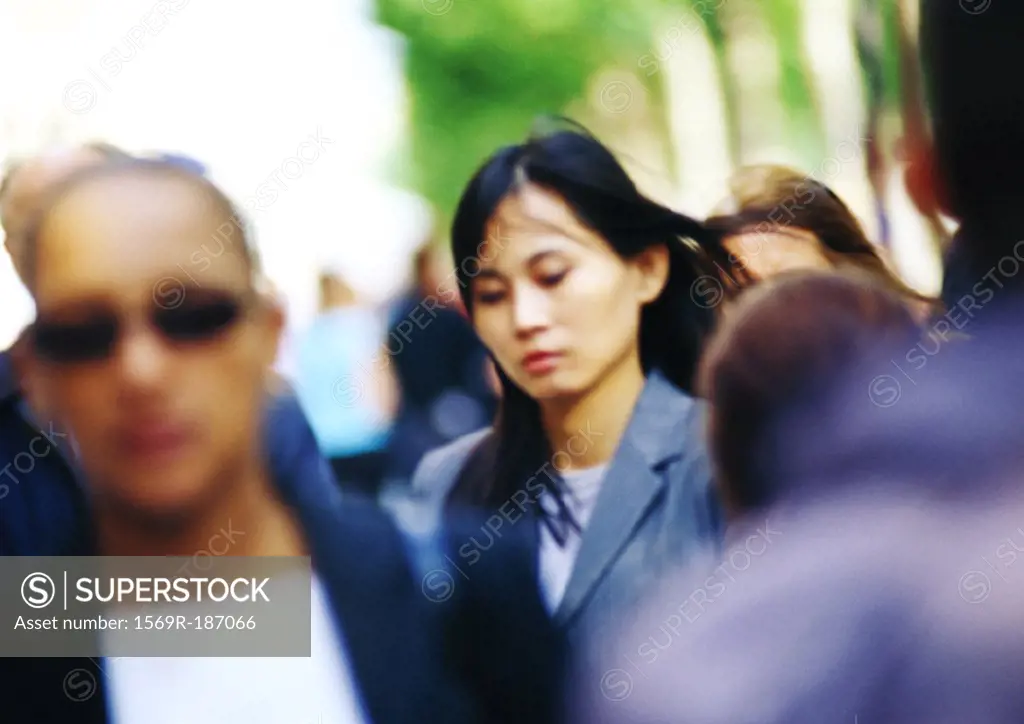 Businesswoman in crowd, head and shoulders, blurred