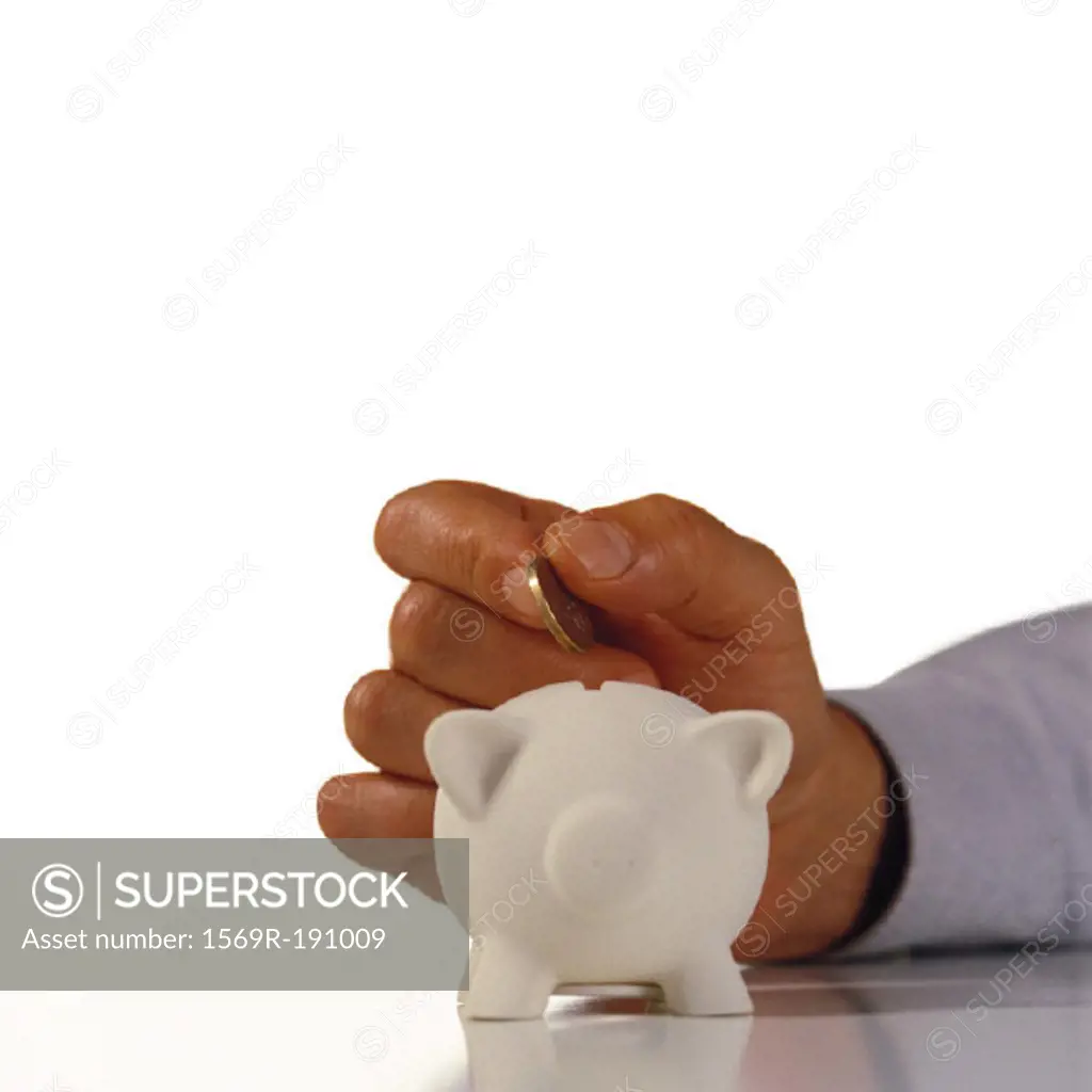 Hand dropping a coin in a piggy bank