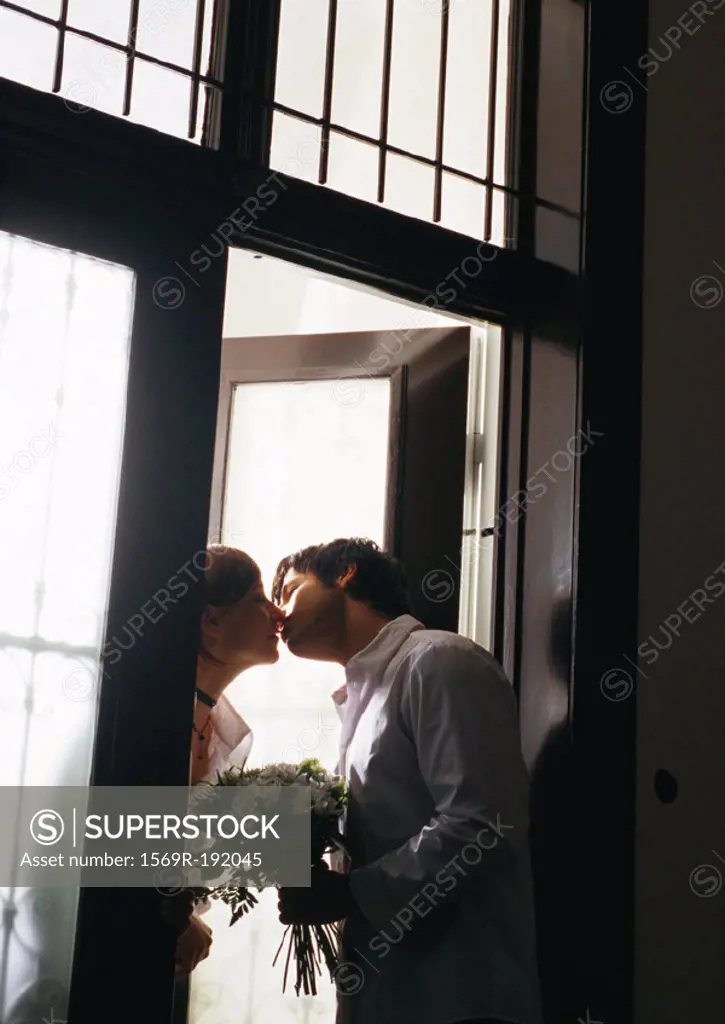 Man kissing woman in doorway, tilt