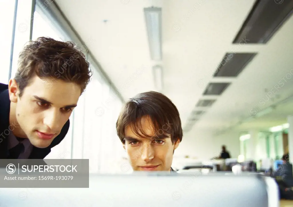 Two men´s heads, edge of computer screen in foreground