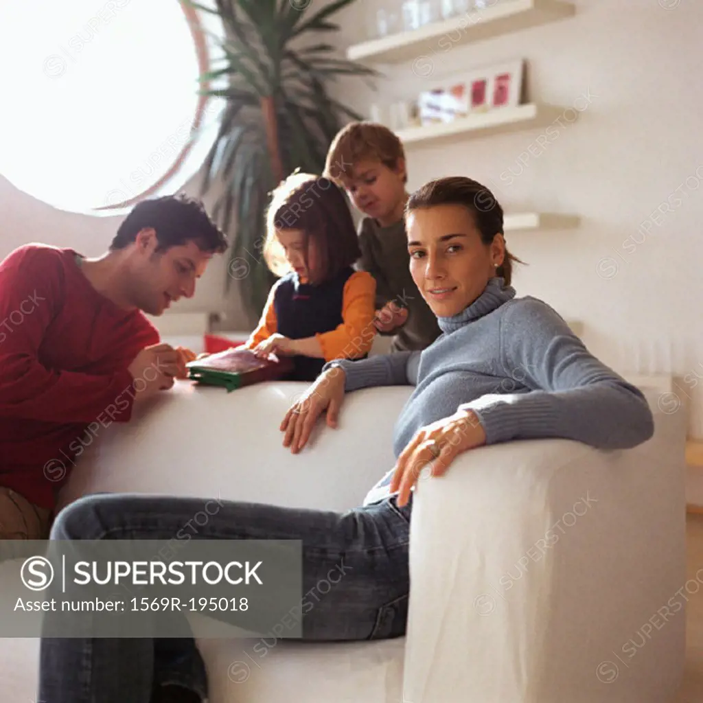 Mother sitting in front of family, playing in background
