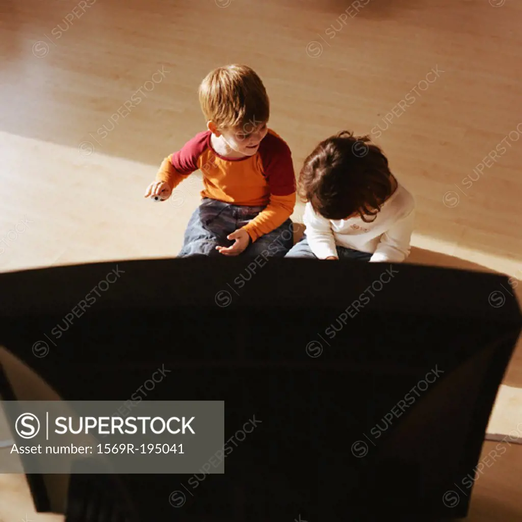 Children sitting on floor together, television in foreground