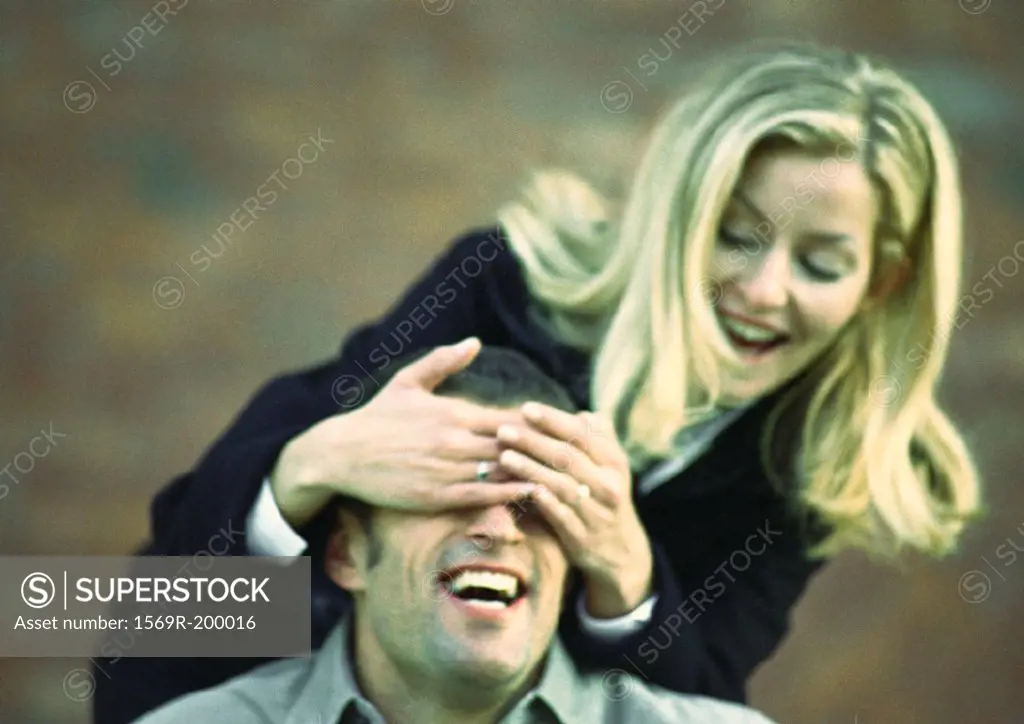 Woman covering man´s eyes from behind with her hands