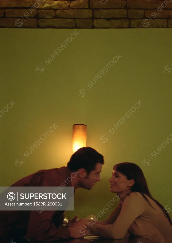 Man leaning forward in front of light to kiss a woman