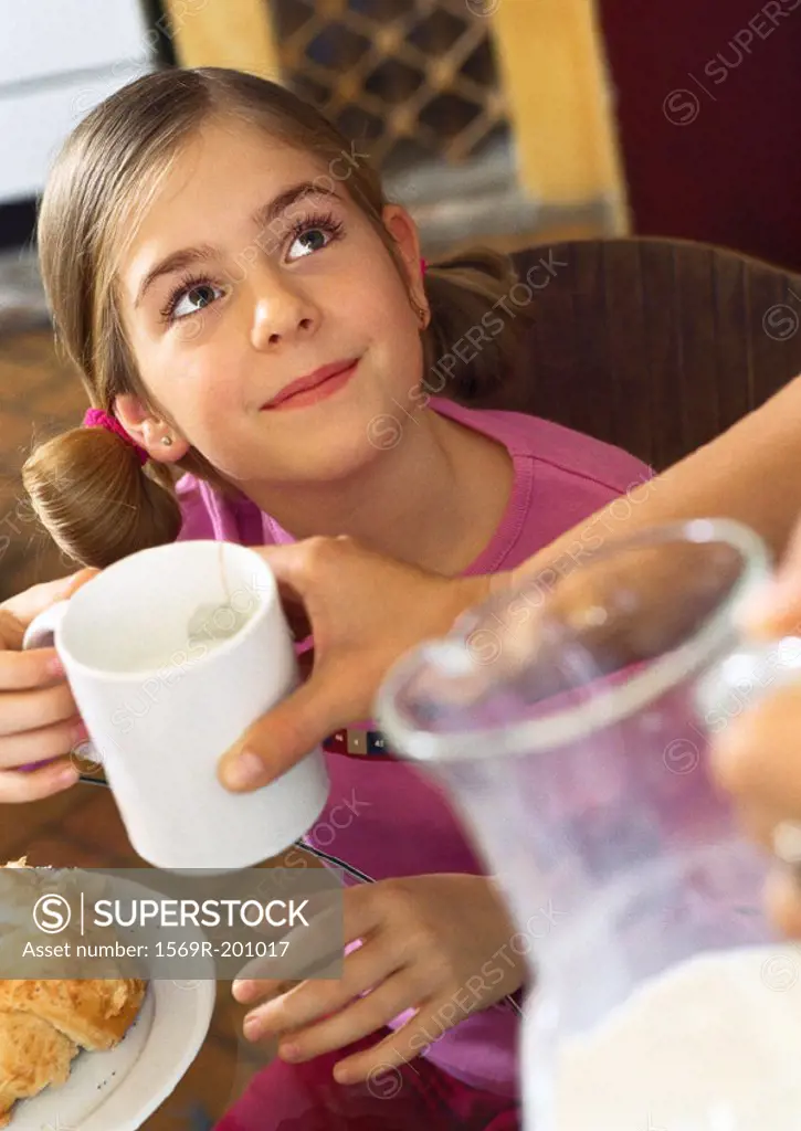 Child looking up, being handed a mug