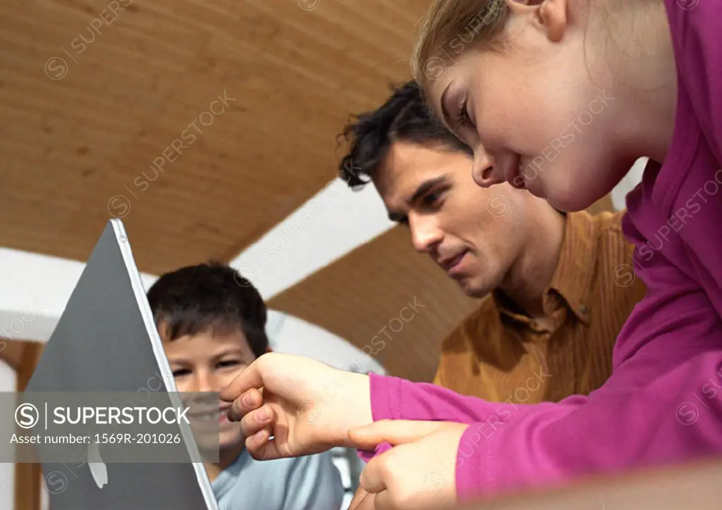 Father, son and daughter looking at laptop computer together