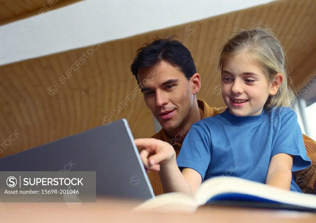 Father and daughter working on computer together