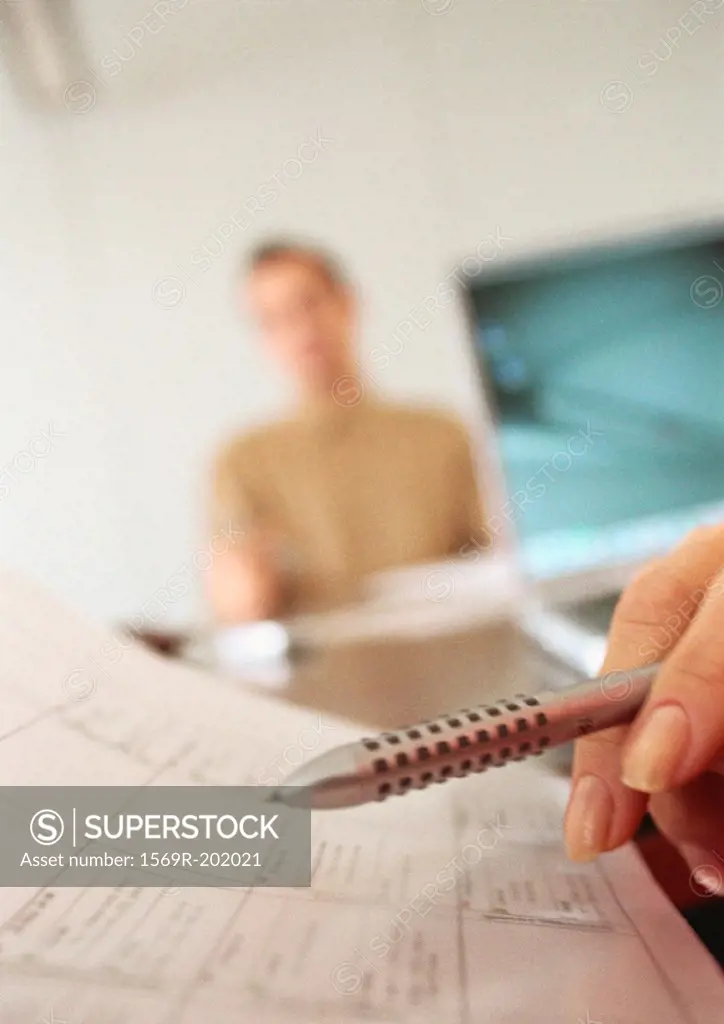 Pen and agenda, and businessman in the background, blurred