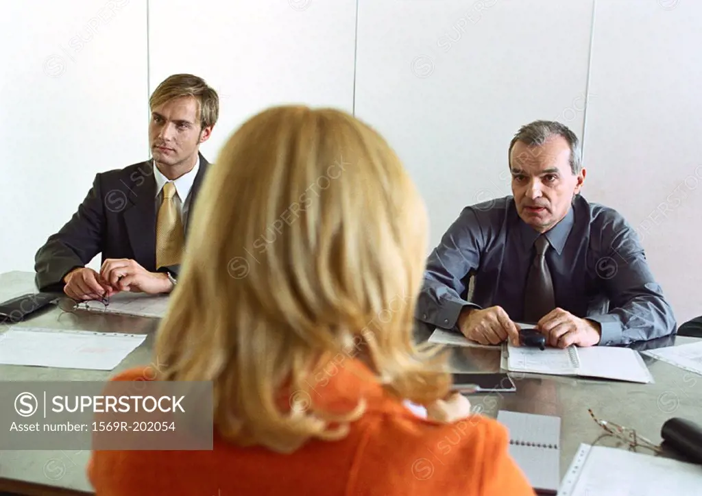 Businessmen and businesswoman sitting at table, woman´s back to camera