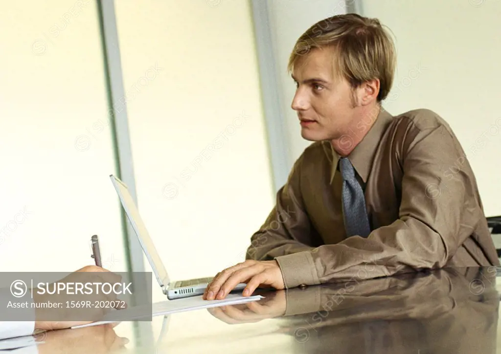 Businessman sitting at table listening to someone