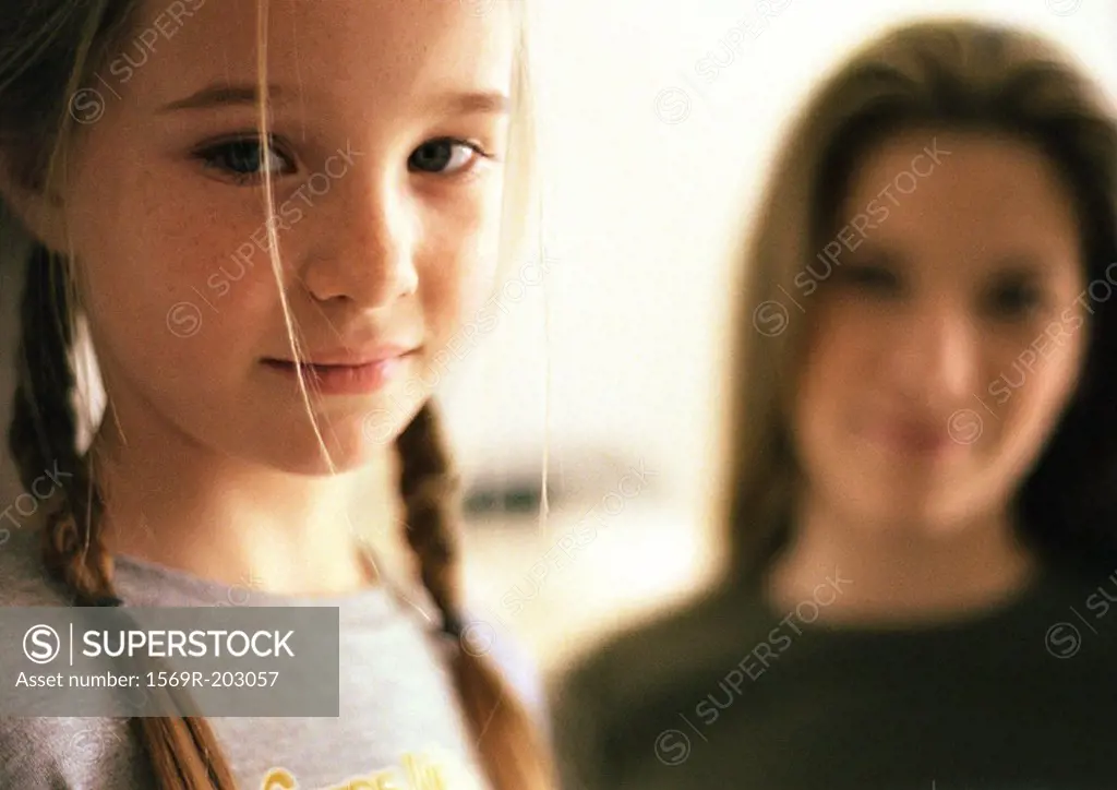 Two girls, little girl in foreground, older girl blurred in background, portrait