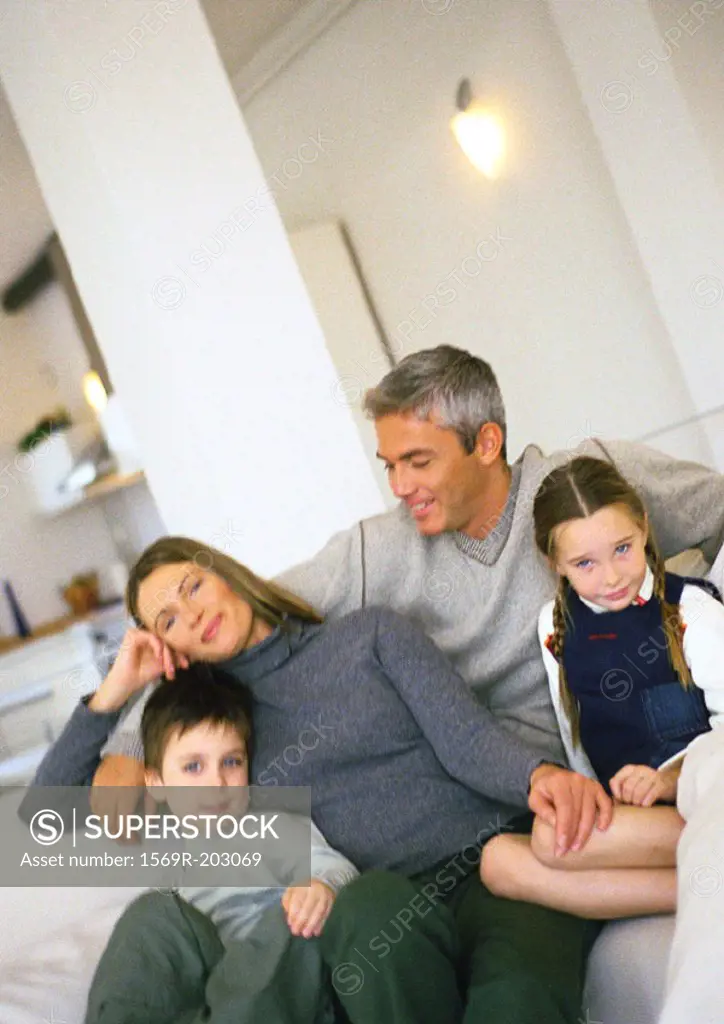 Family sitting on couch in living room, portrait