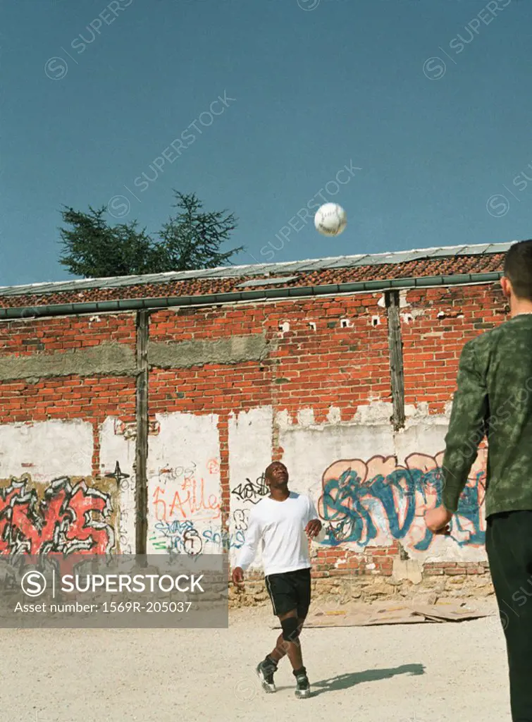 Men playing with soccer ball in urban setting