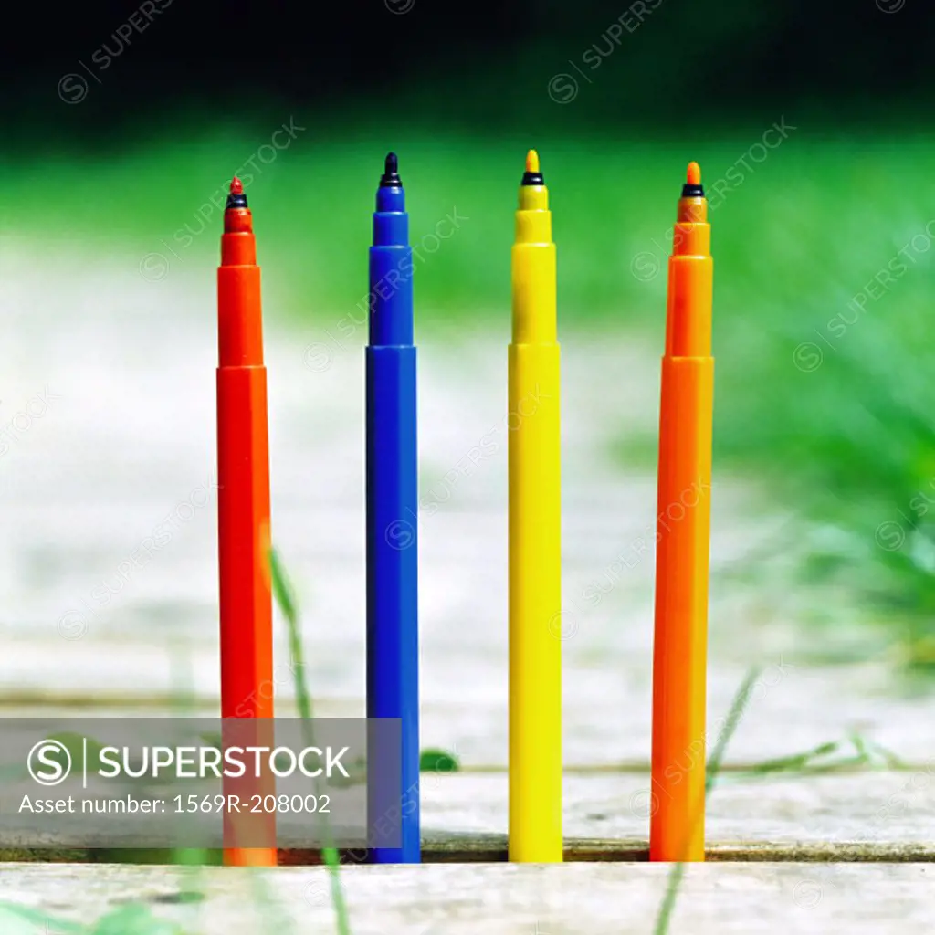 Colored felt-tip pens sticking out of ground