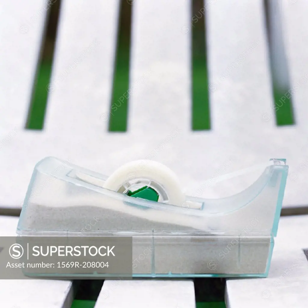 Adhesive tape dispenser on plastic lounge chair, close-up