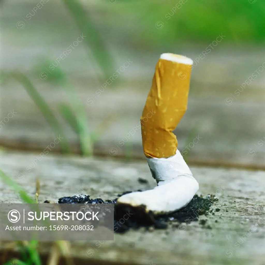 Discarded cigarette butt on ground, close-up