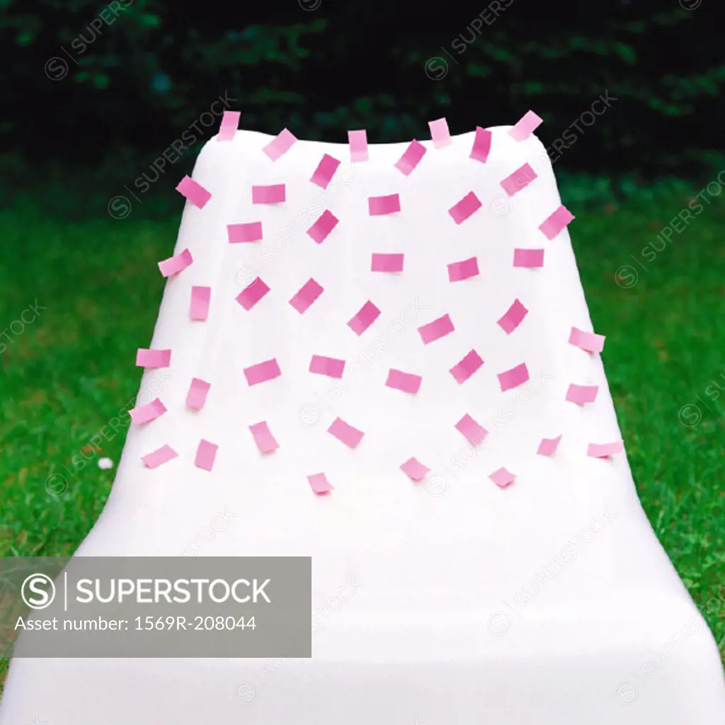 Pink adhesive notes stuck onto white plastic chair