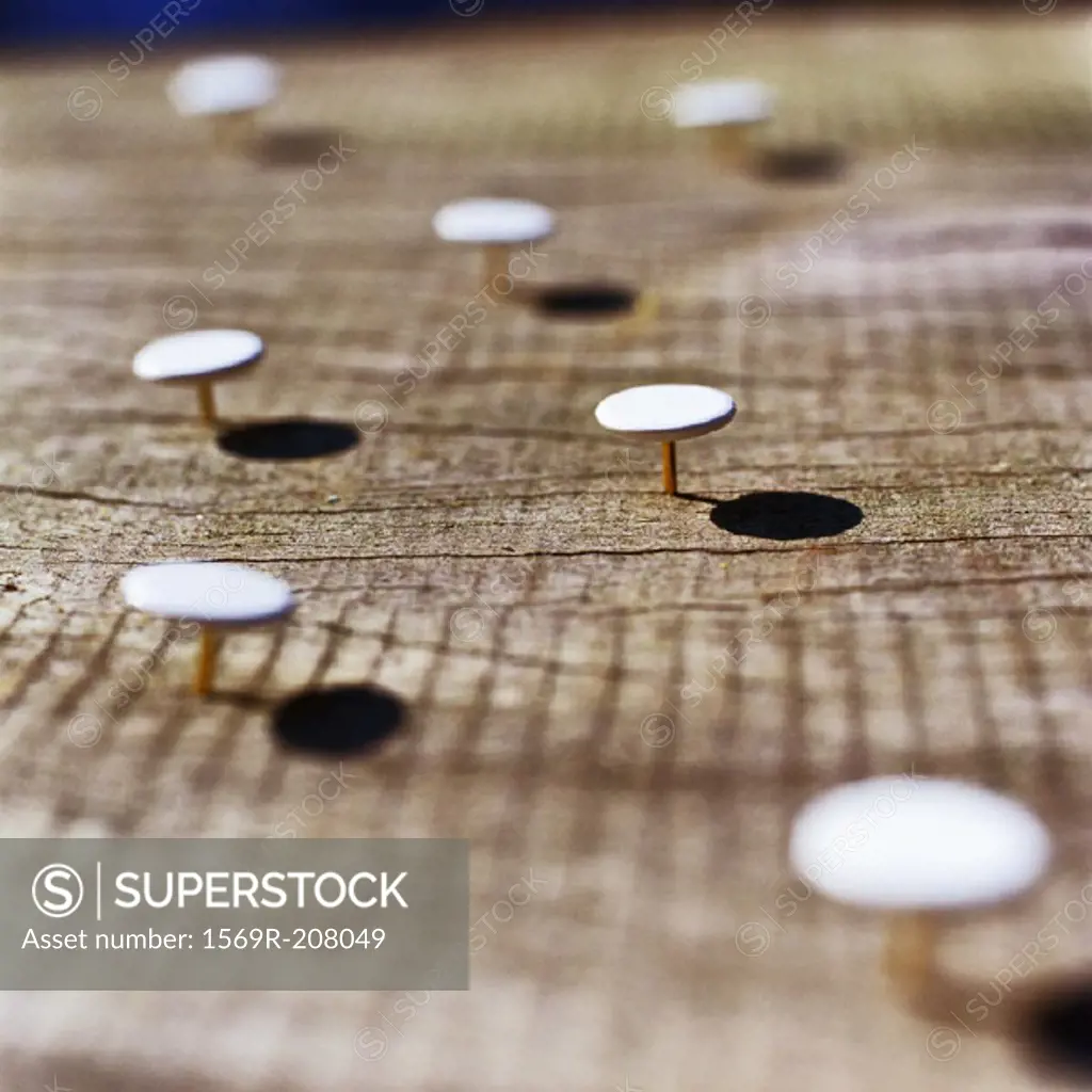 Thumbtacks stuck into wooden surface