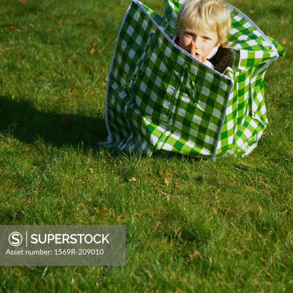 Child in laundry bag with finger over lips