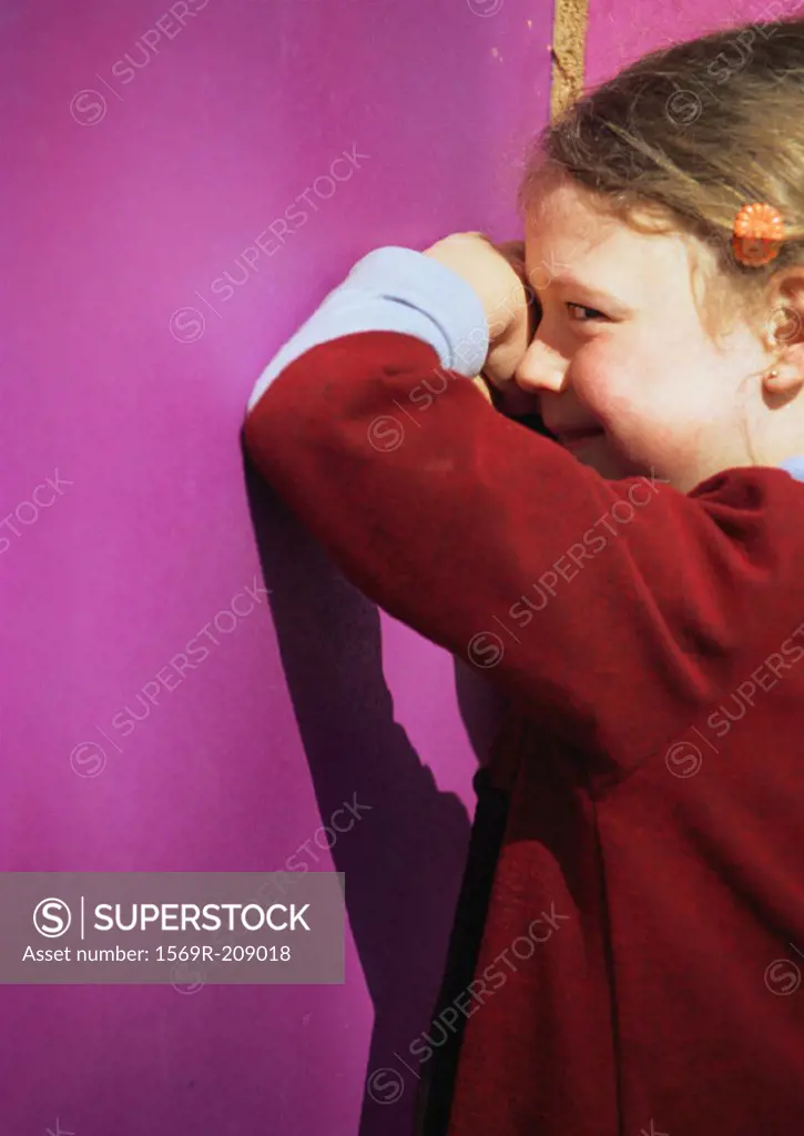 Little girl facing wall, smiling