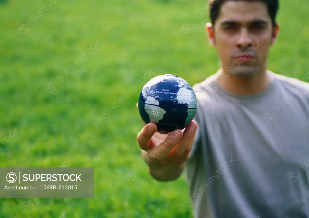 Man holding out small globe