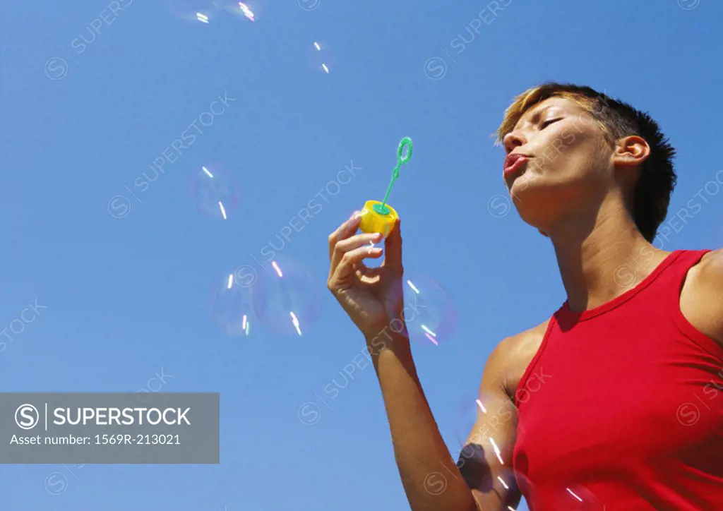 Woman blowing bubbles, low angle view