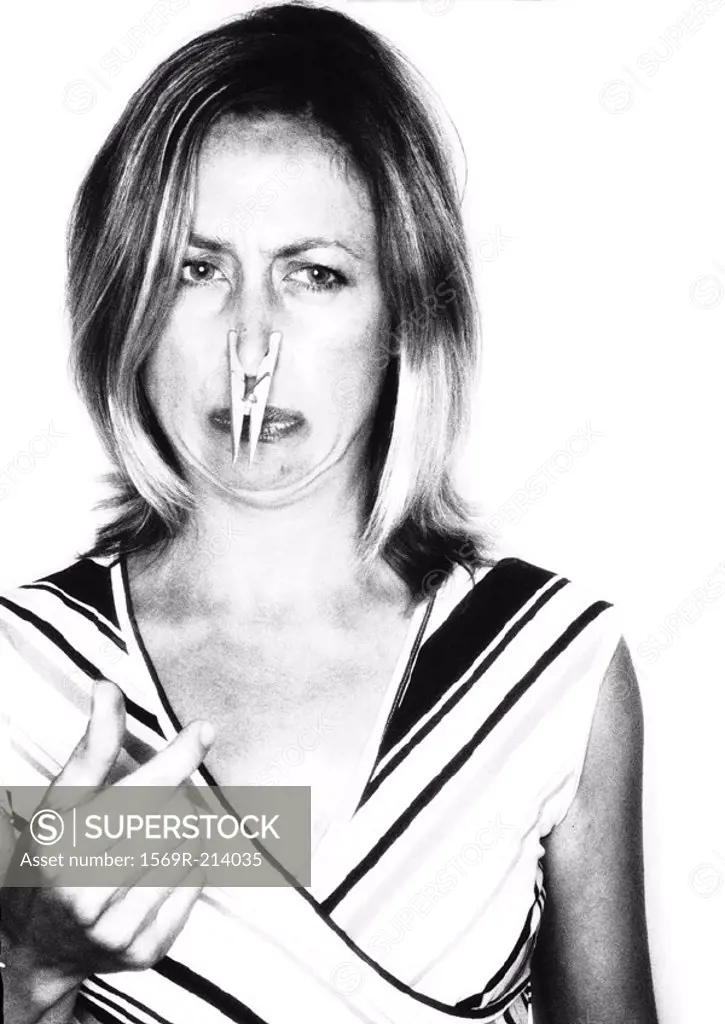 Woman frowning, clothes peg on nose, portrait, b&w