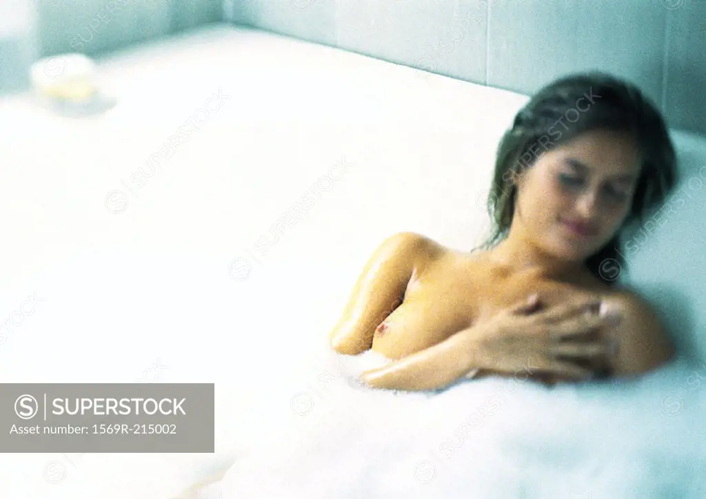 Woman in bubble bath, hand over left breast