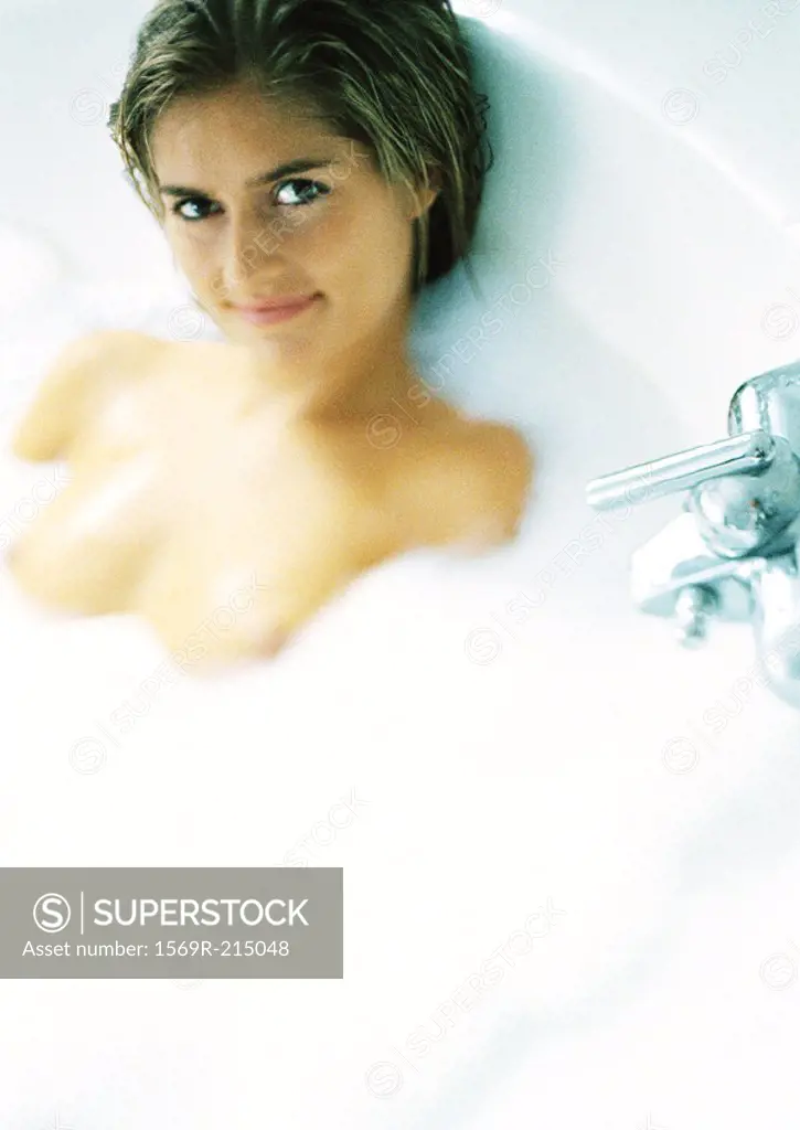 Woman in a bubble bath, smiling at camera