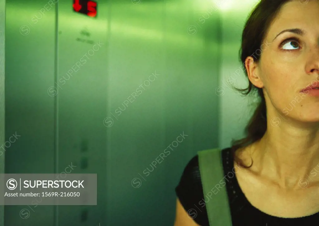 Woman in elevator looking up, partial view, close-up