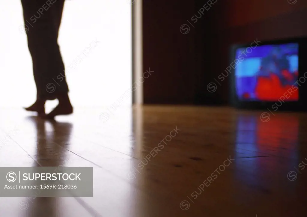 Man walking past television, low angle