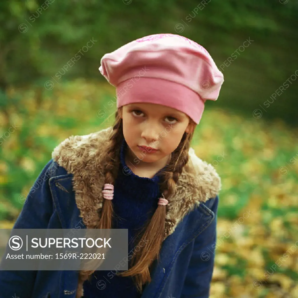 Girl outside wearing hat and coat, pouting, looking at camera
