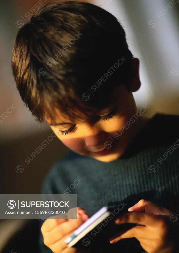 Young boy playing with hand held personal assistant, close up