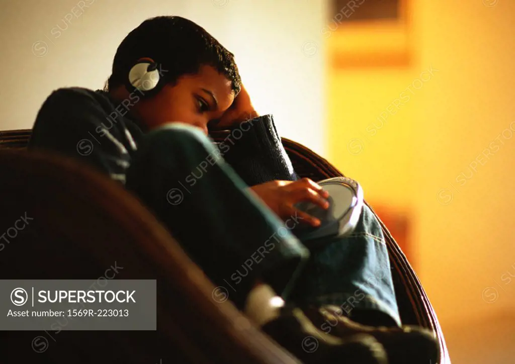 Young boy sitting in chair listening to music with headphones