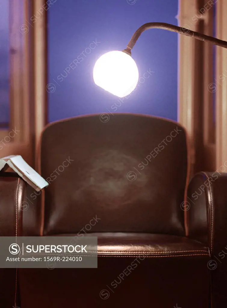 Light shining over chair with open book on arm