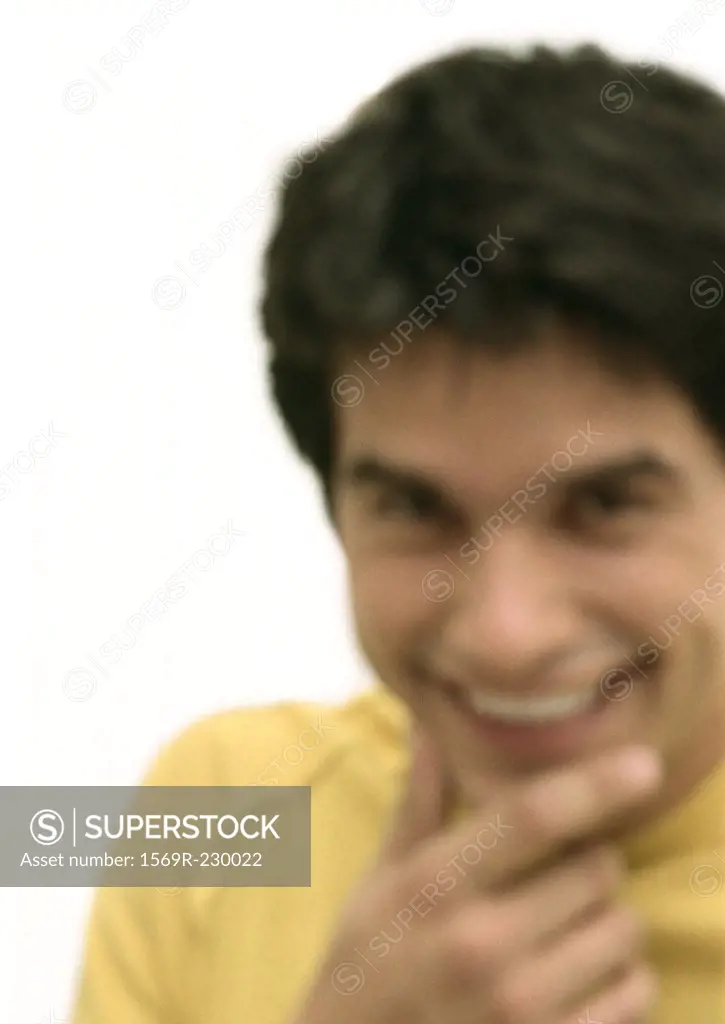 Man smiling, hand to chin, blurred portrait