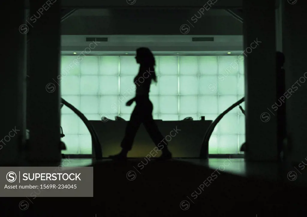 Woman walking in front of desk, silhouette, view through doorway