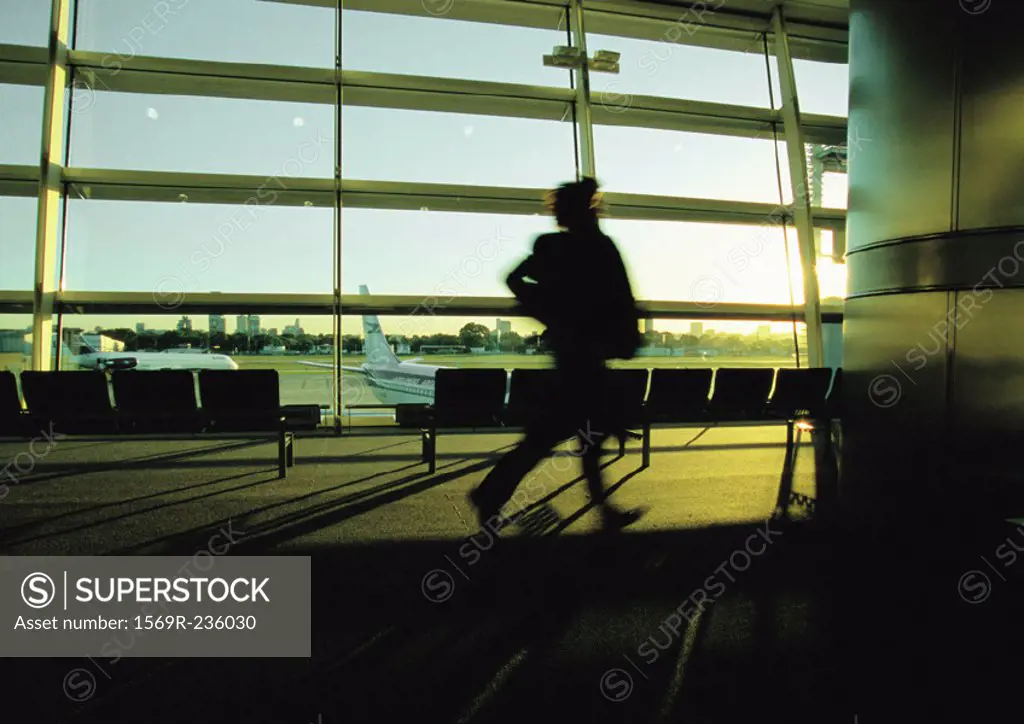 Silhouette of businessperson hurrying through airport terminal