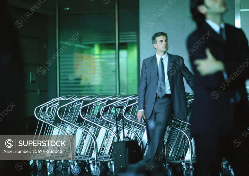 Businessmen standing in front of airport luggage carts