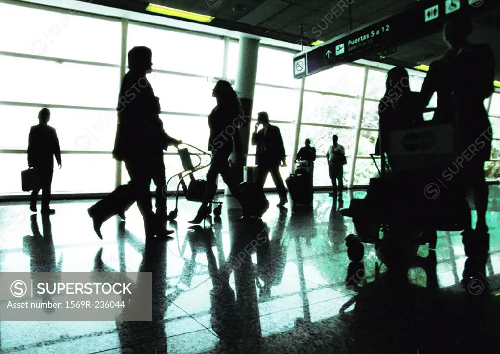 Silhouettes of business people walking in airport terminal, backlit