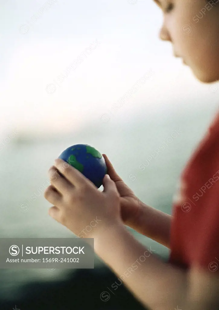 Child holding ball, close-up, blurred