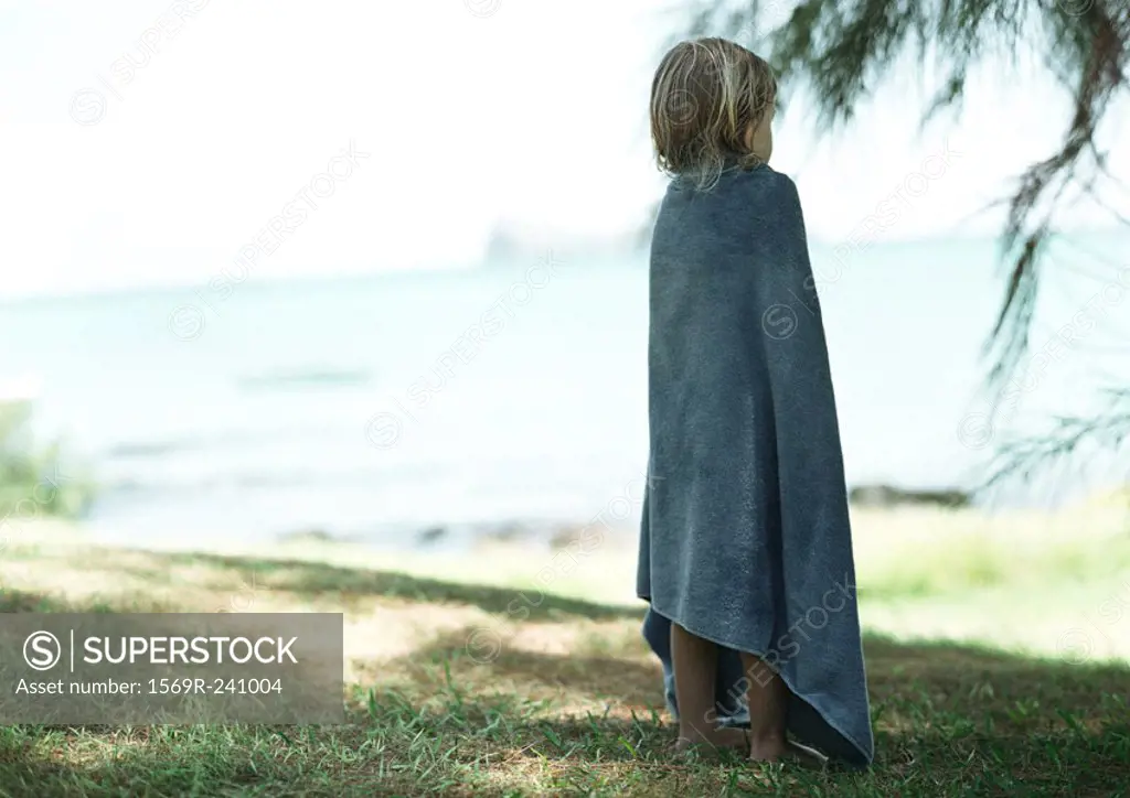 Child wrapped in towel, outside, rear view