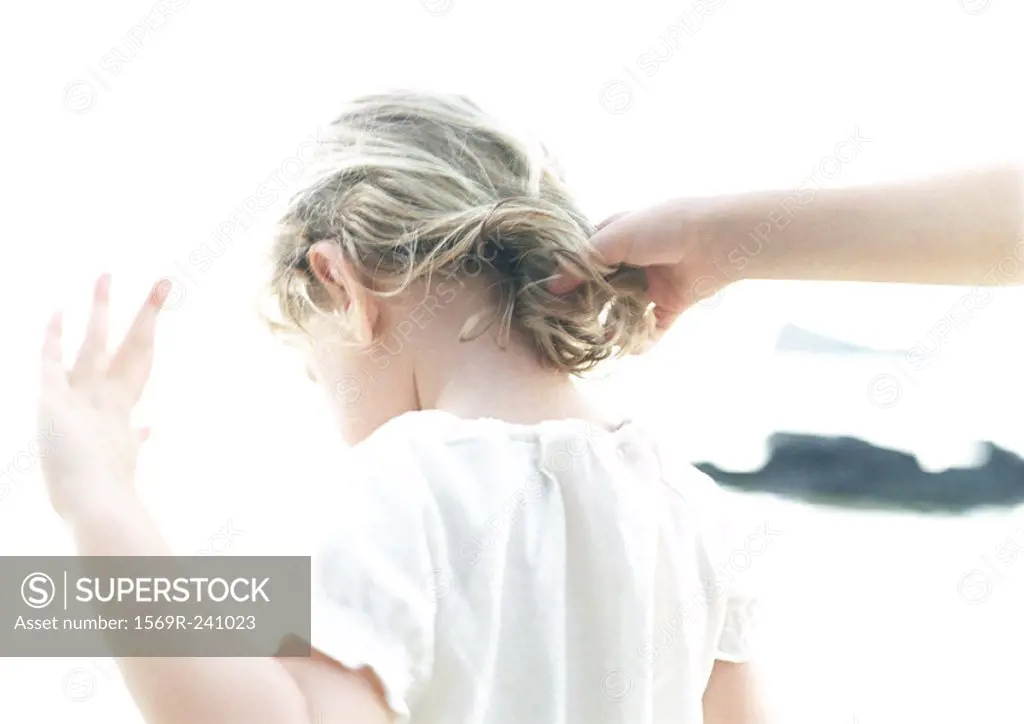 Hand touching child´s hair, rear view, blurred