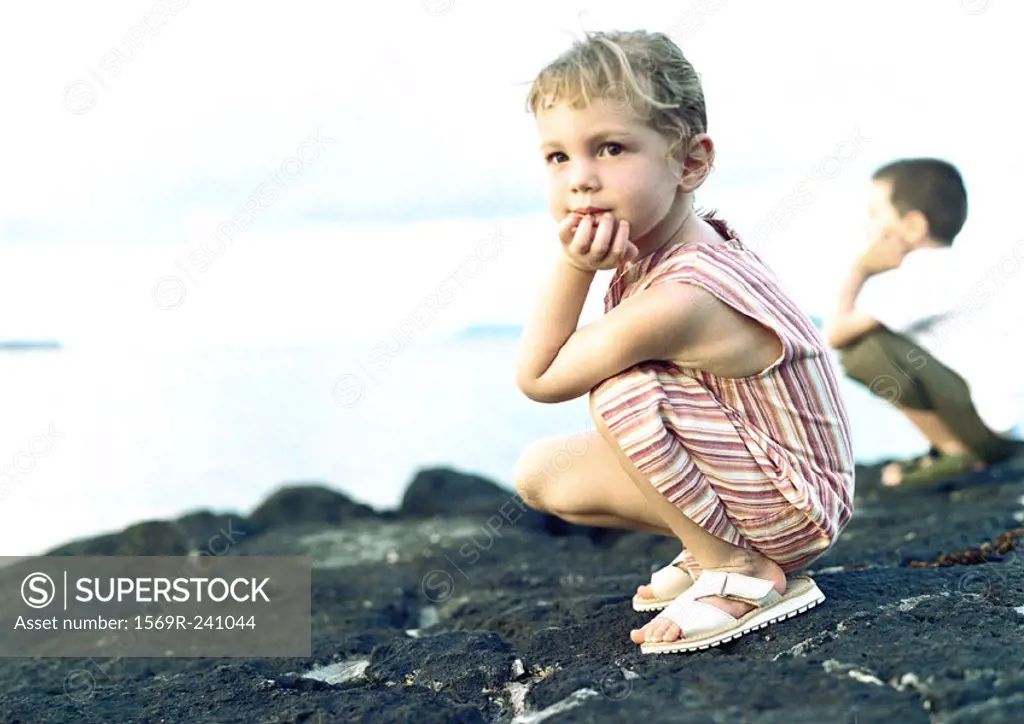 Two children crouching on rock
