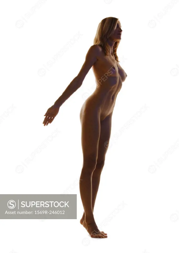 Nude woman standing on tiptoes with arms back, full length