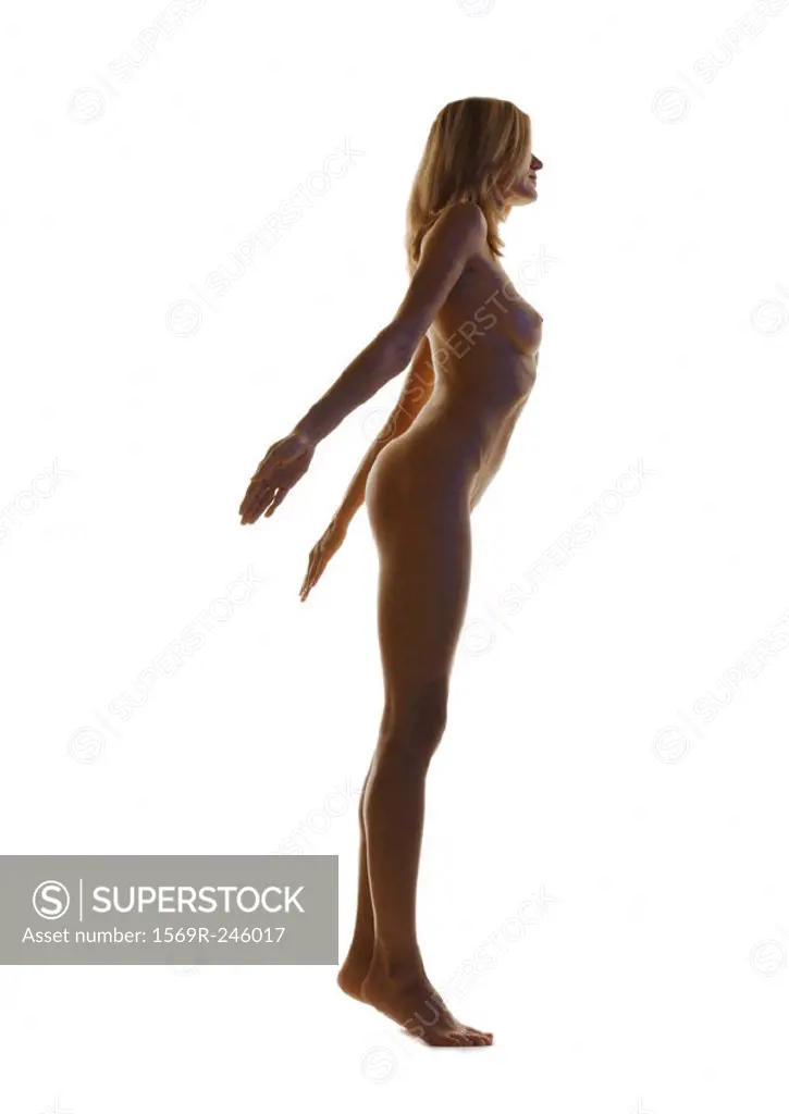 Nude woman standing with arms back, full length, side view