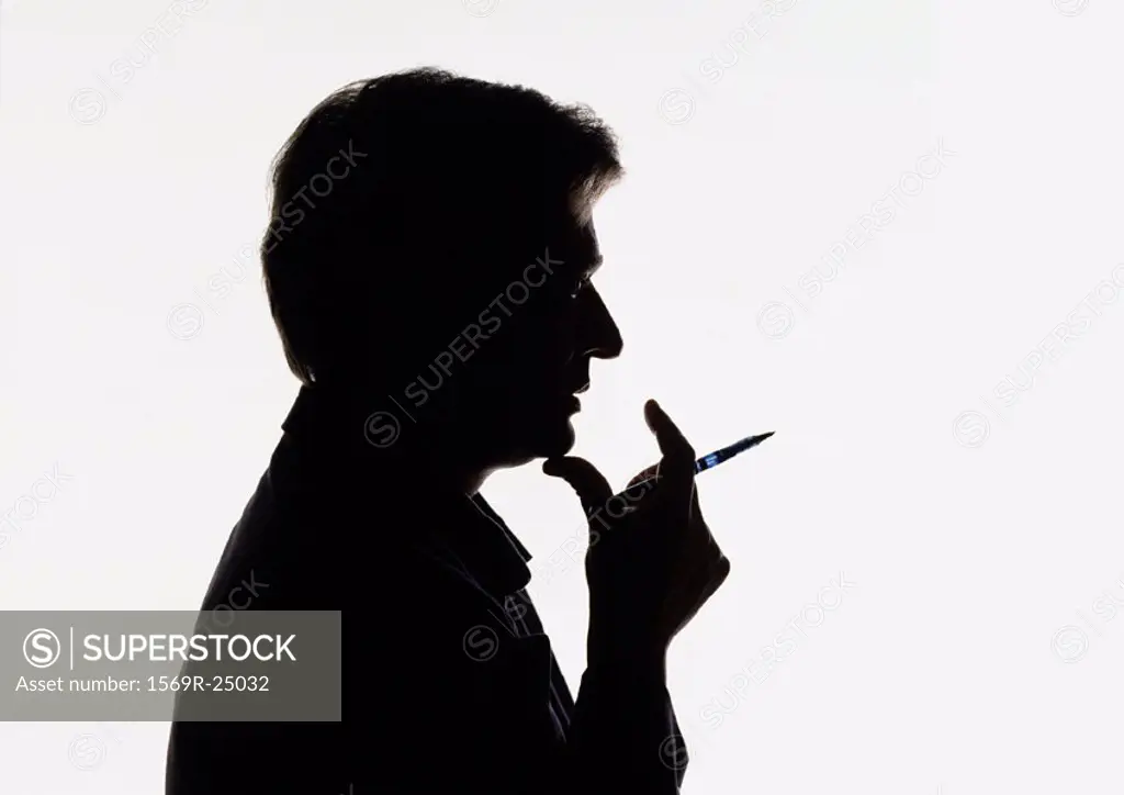 Man holding pen near mouth, silhouette