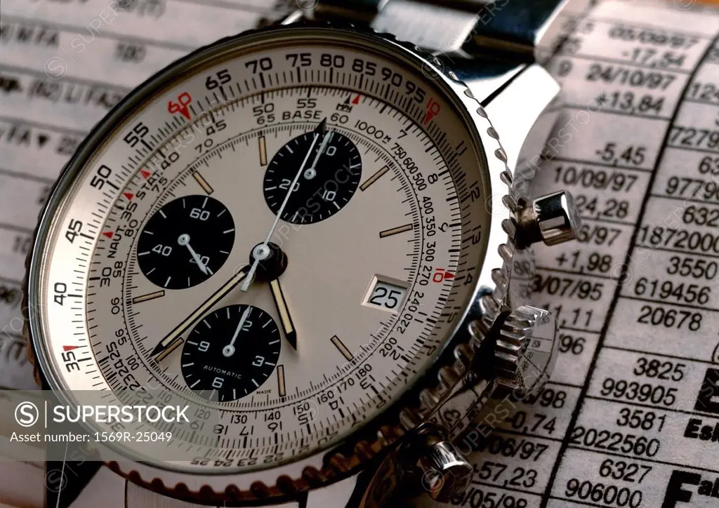 Wristwatch on top of stock report, extreme close-up