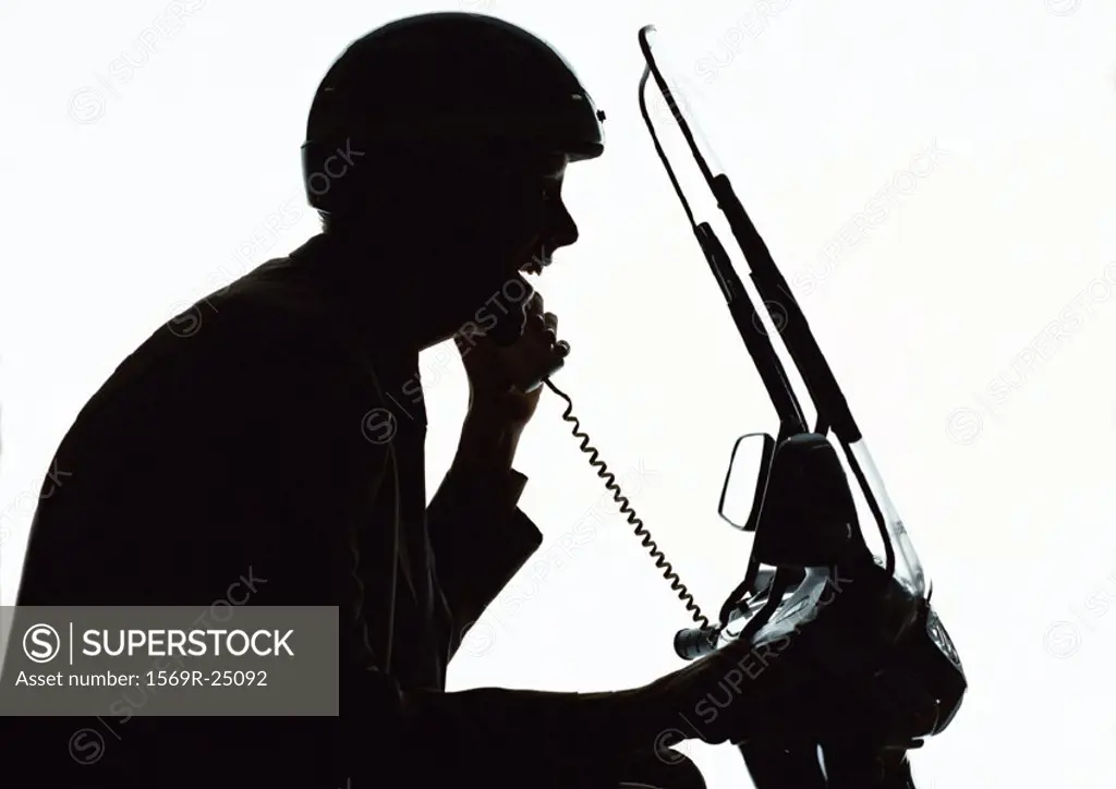 Man using phone on motorcycle, silhouette